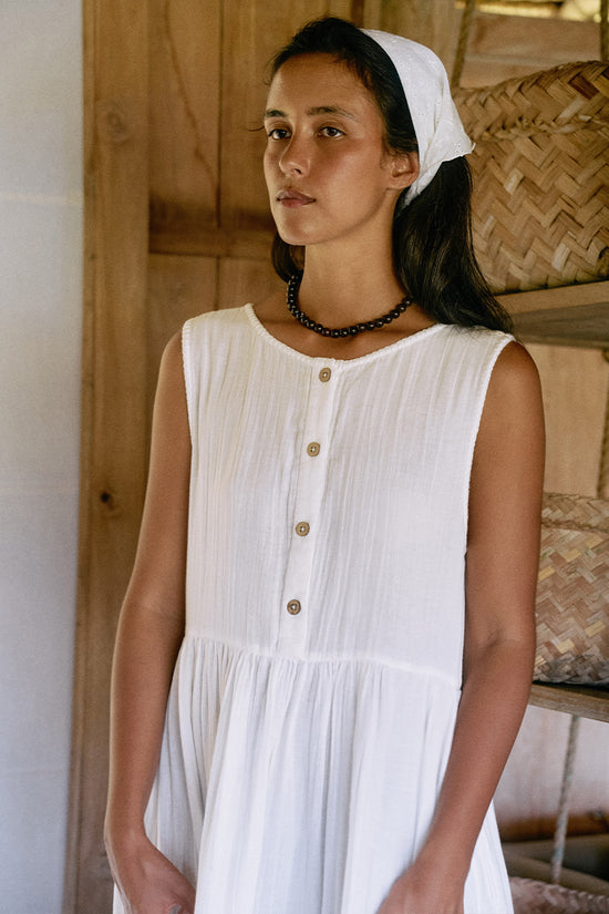 Nadi Dress White — bodice close-up showing wooden button front detail, round neckline, white double gauze cotton fabric texture, gathered waist | Daughters of India