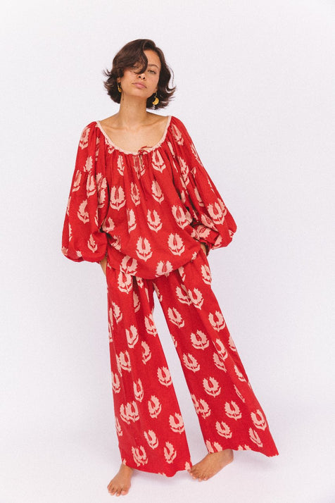 Ria Pants Ruby Red — studio side view detail, model wearing ruby red hand block print cotton wide-leg pants showing flowing silhouette, botanical leaf motif, artisan Jaipur India | Daughters of India