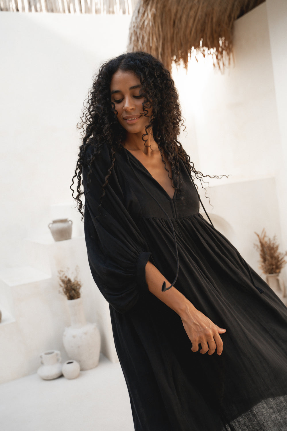 Daughters of India Kyra Midi Dress in Black Gauze — upper body V-neckline and billowed sleeves, smiling, cotton gauze
