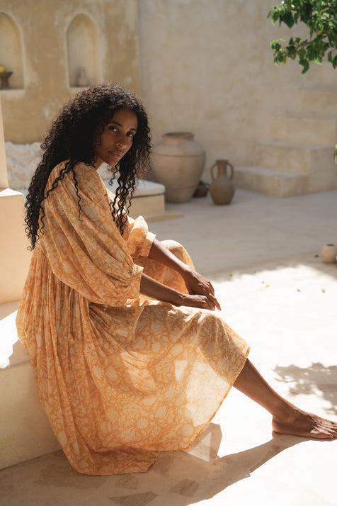 Daughters of India Kyra Midi Dress in Tangerine — seated in sunlit courtyard, hand screen print cotton